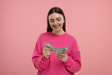 Photo of Happy woman with dollar banknotes on pink background