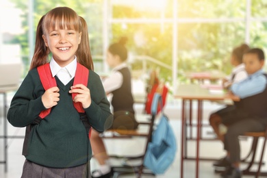 Image of Happy girl with backpack in school classroom