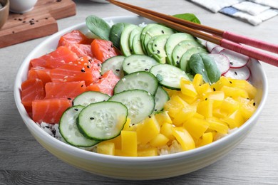 Photo of Delicious poke bowl with salmon and vegetables served on wooden table, closeup