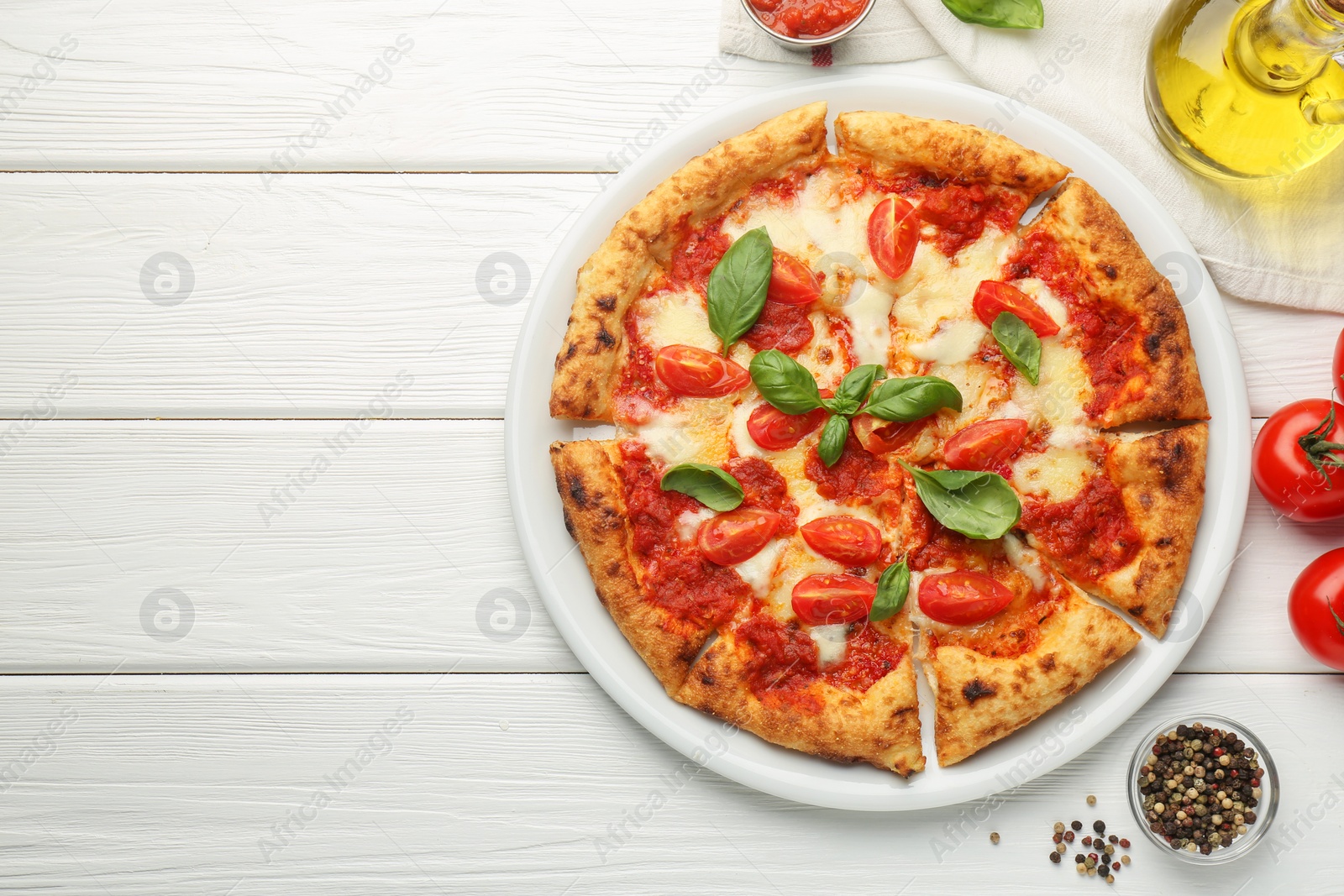Photo of Delicious Margherita pizza and ingredients on white wooden table, top view. Space for text