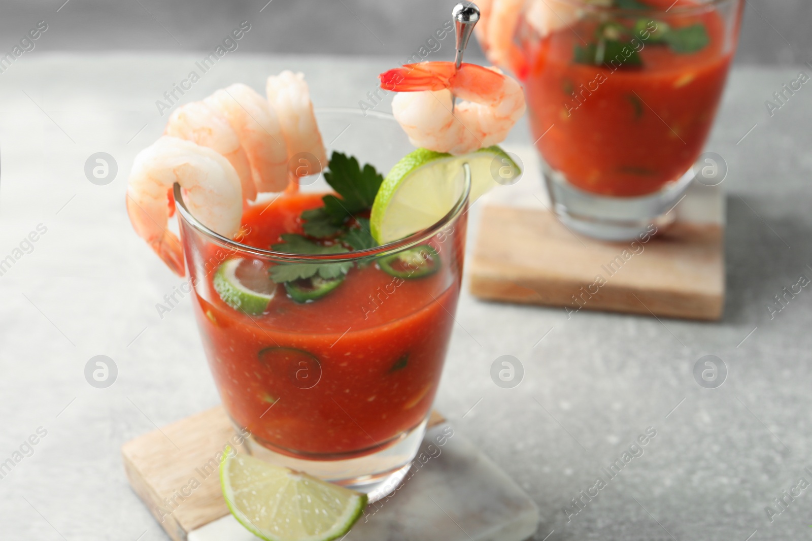 Photo of Tasty shrimp cocktail with sauce in glasses and lime on light grey table