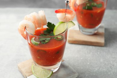 Tasty shrimp cocktail with sauce in glasses and lime on light grey table
