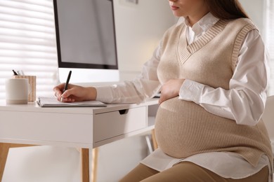 Photo of Pregnant woman working at home, closeup. Maternity leave