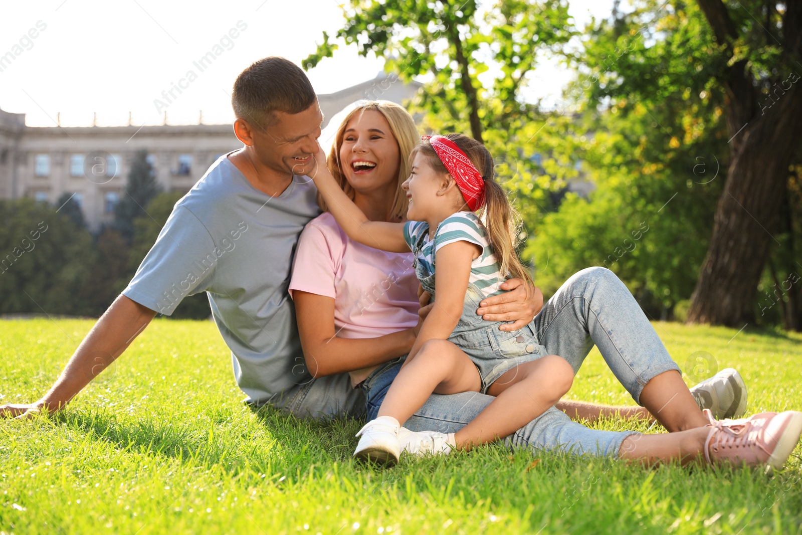 Photo of Happy parents with their child having fun on green grass. Spending time in nature