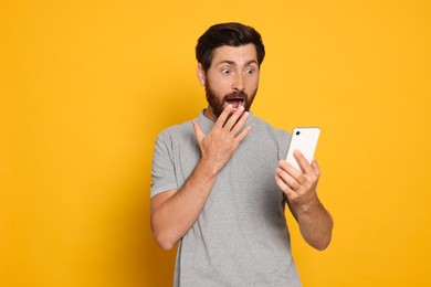 Photo of Emotional man with smartphone against yellow background
