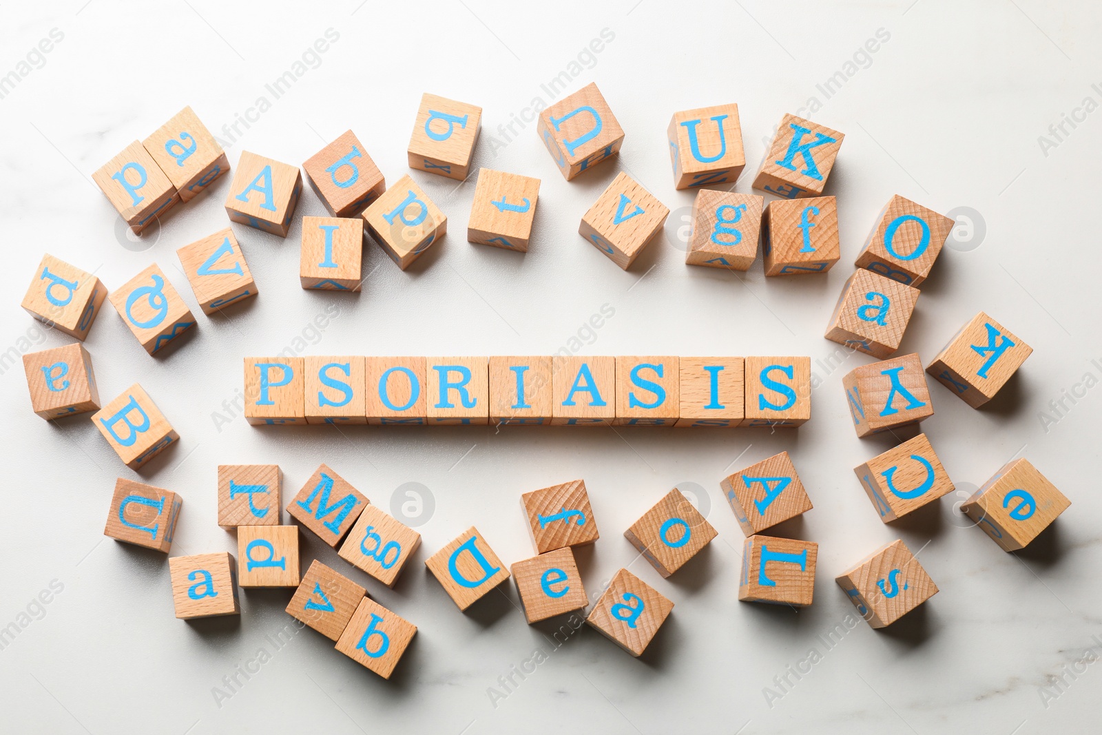 Photo of Word Psoriasis made of wooden cubes with letters on white marble table, flat lay
