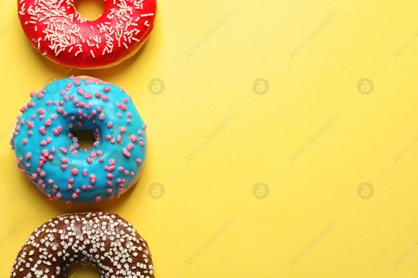 Photo of Delicious glazed doughnuts on color background, top view