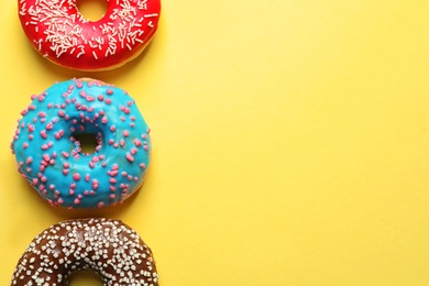 Photo of Delicious glazed doughnuts on color background, top view