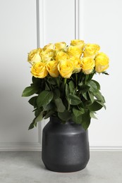 Photo of Beautiful bouquet of yellow roses in vase on light grey table near white wall