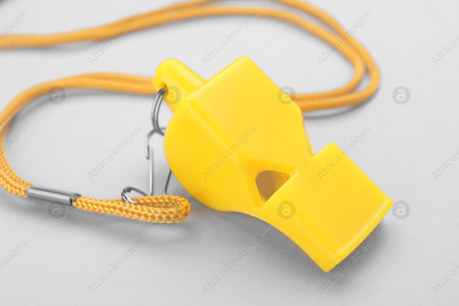 Photo of One yellow whistle with cord on white background, closeup
