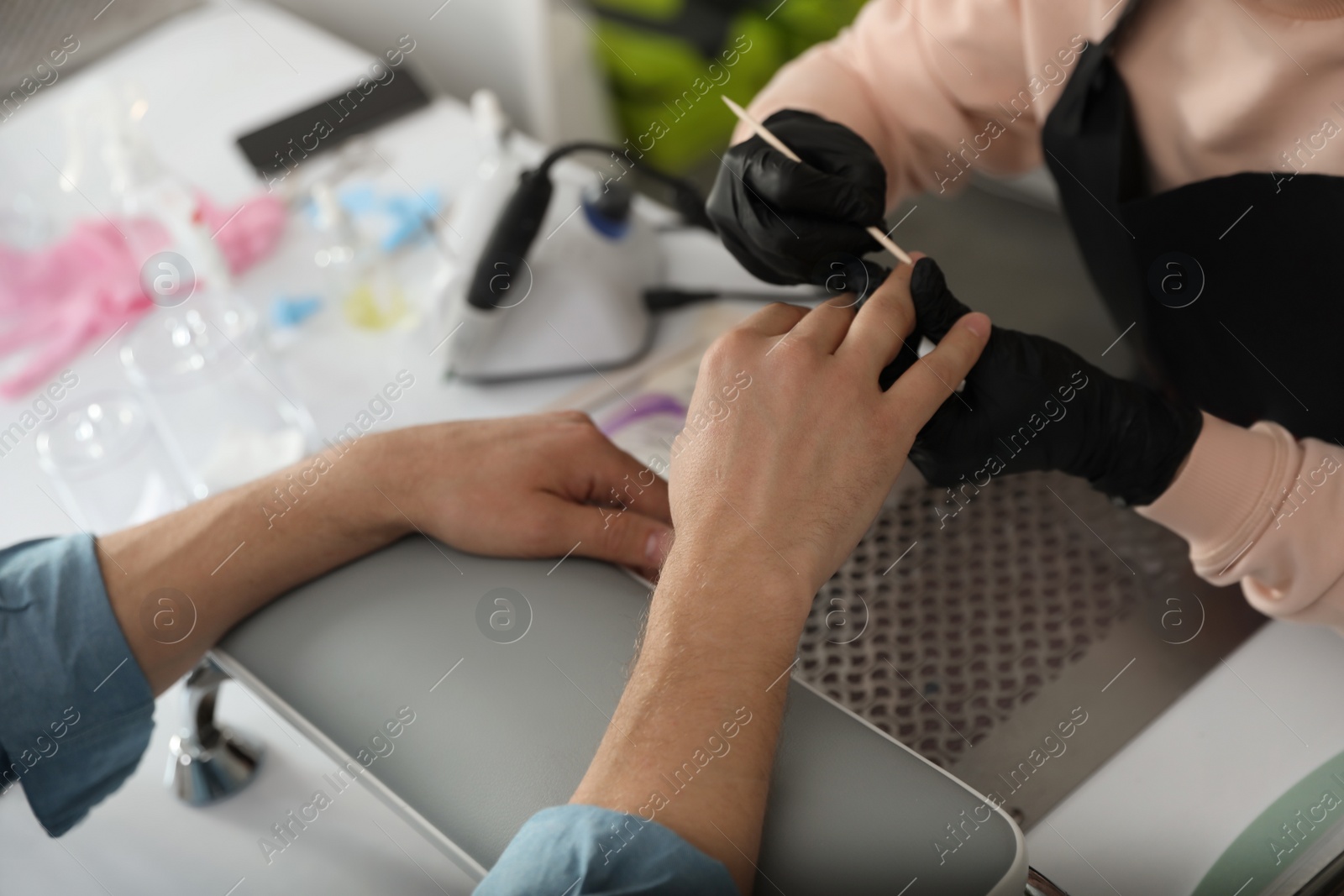 Photo of Professional manicurist working with client in beauty salon, closeup