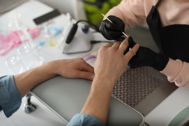 Photo of Professional manicurist working with client in beauty salon, closeup