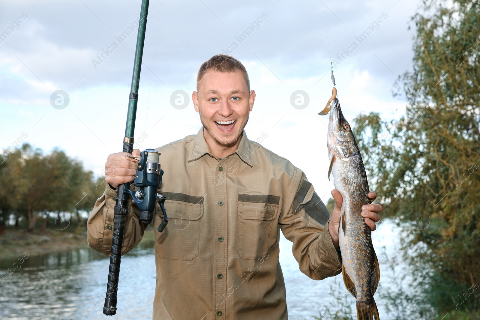 Photo of Man with rod and catch fishing at riverside. Recreational activity