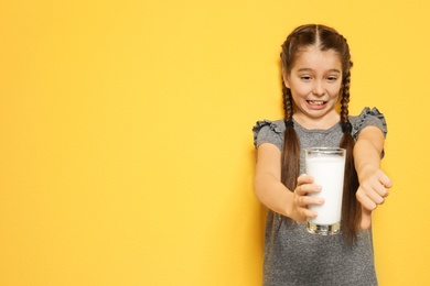 Photo of Little girl with dairy allergy holding glass of milk on color background