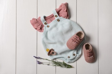 Photo of Children's shoes, clothes, pacifier and lavender on white wooden table