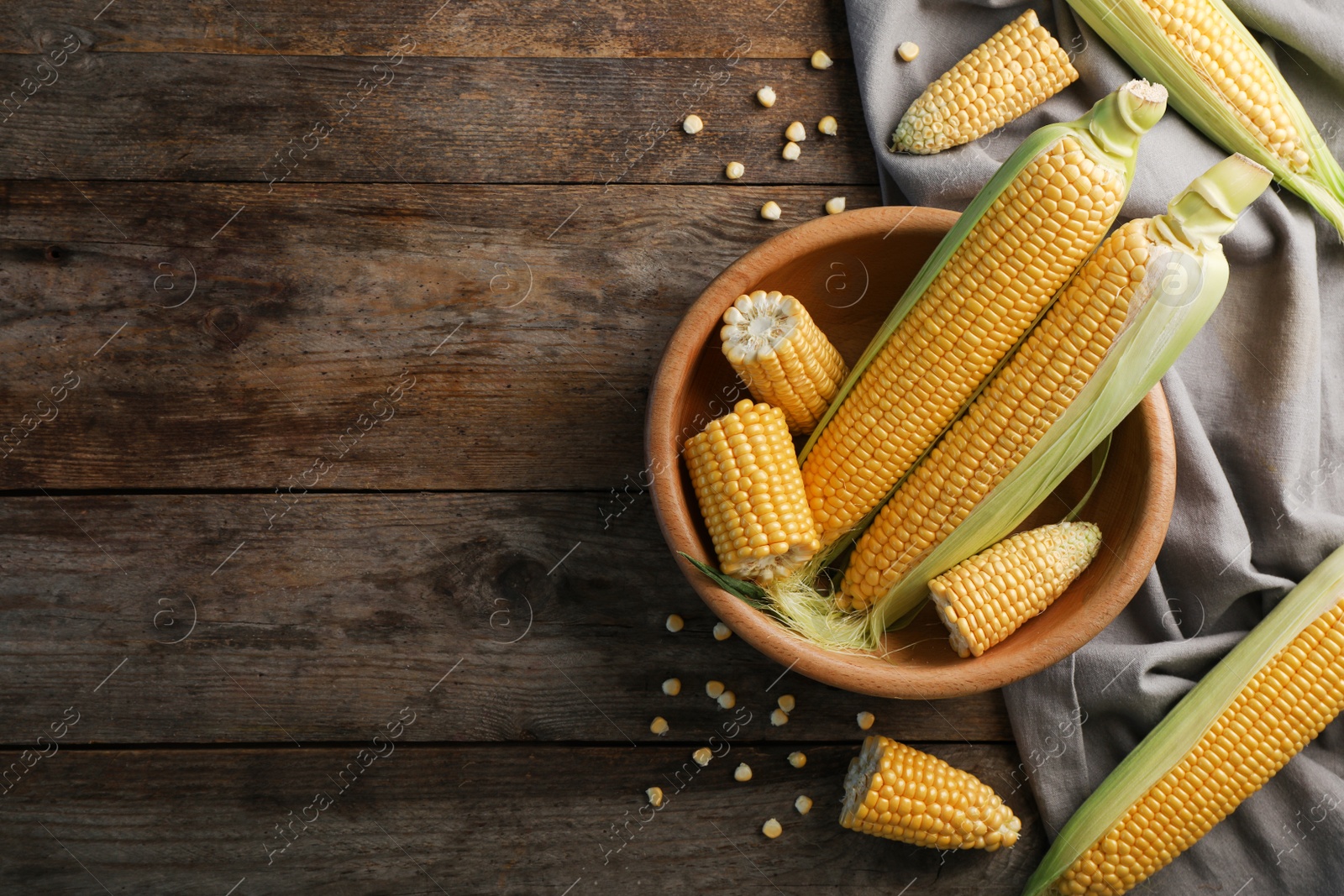 Photo of Tasty sweet corn cobs on wooden table, top view