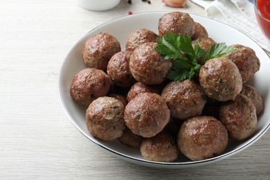 Photo of Tasty cooked meatballs with parsley on white wooden table