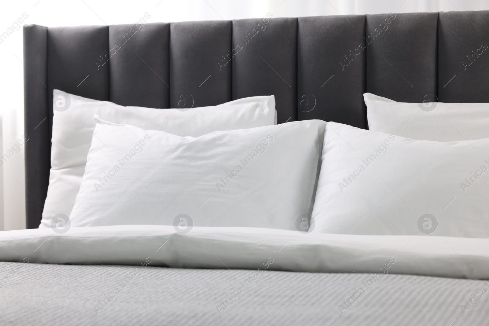 Photo of Soft white pillows and duvet on bed