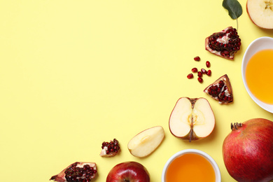 Honey, apples and pomegranates on yellow background, flat lay with space for text. Rosh Hashanah holiday