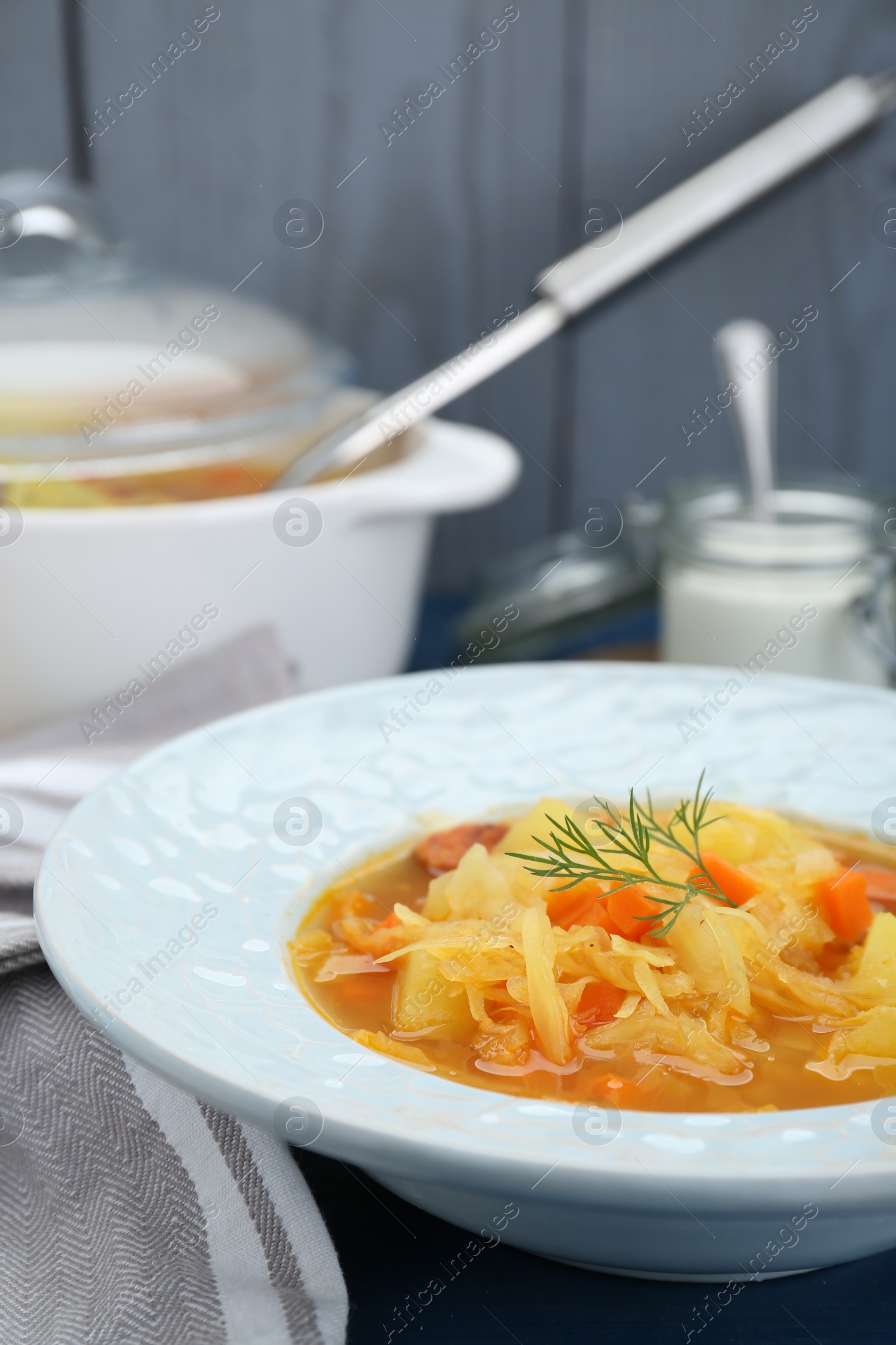 Photo of Delicious sauerkraut soup with carrot and dill on table, closeup