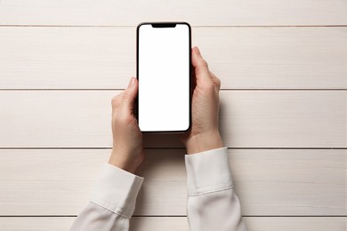 Photo of Woman with smartphone at white wooden table, top view