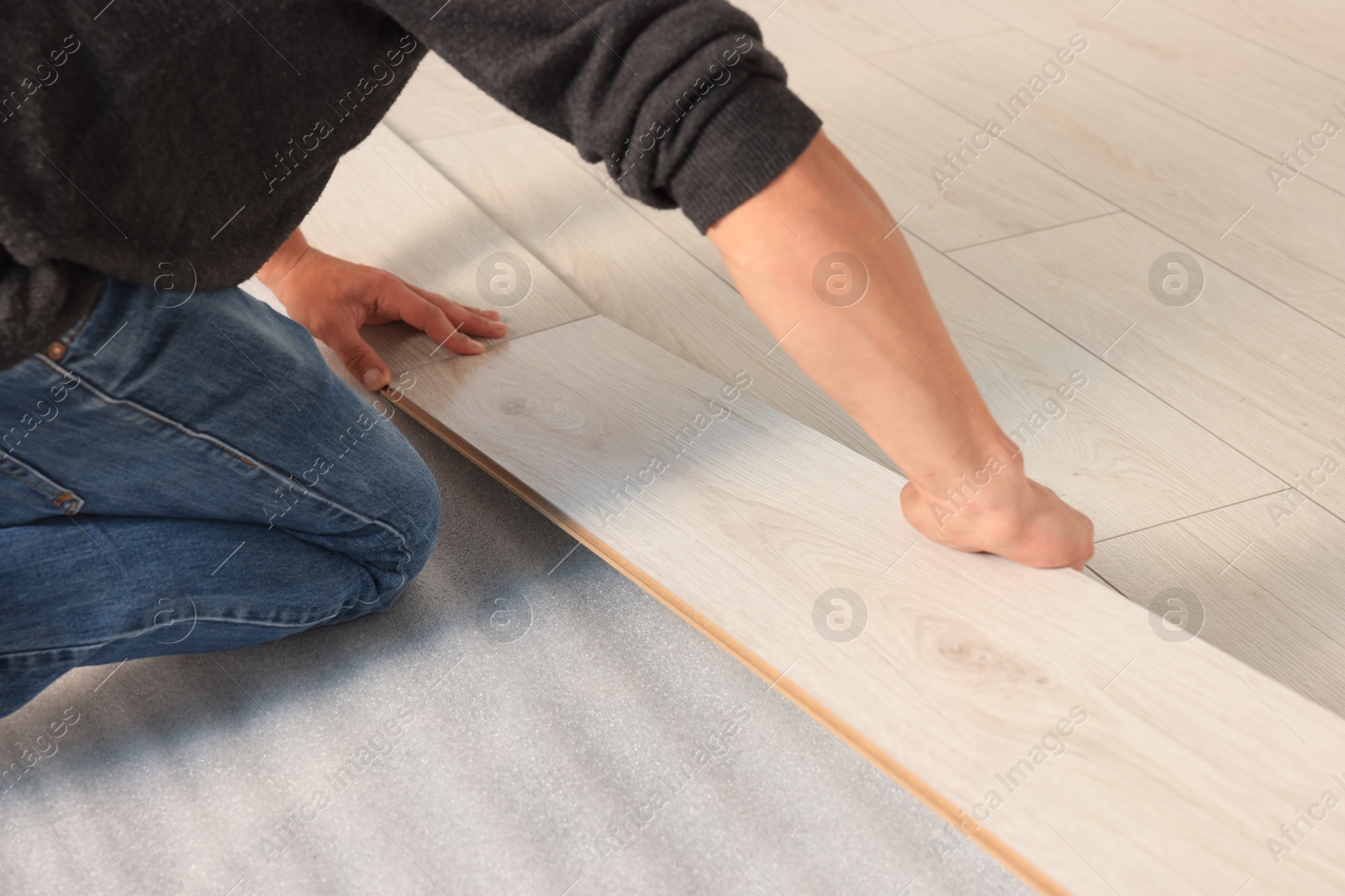 Photo of Professional worker installing new laminate flooring, closeup