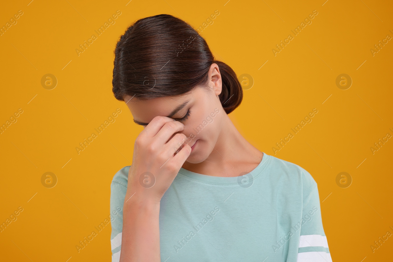 Photo of Embarrassed young woman covering face with hand on orange background