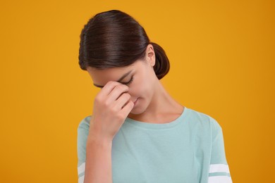 Photo of Embarrassed young woman covering face with hand on orange background