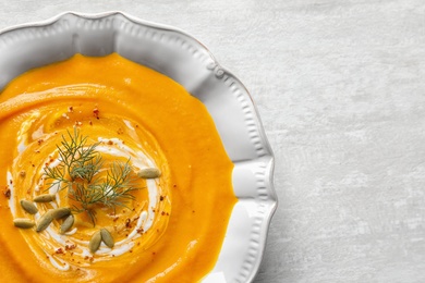 Photo of Bowl of tasty pumpkin soup and space for text on table, top view