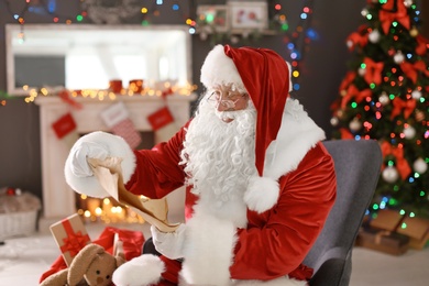 Photo of Authentic Santa Claus reading wish list indoors