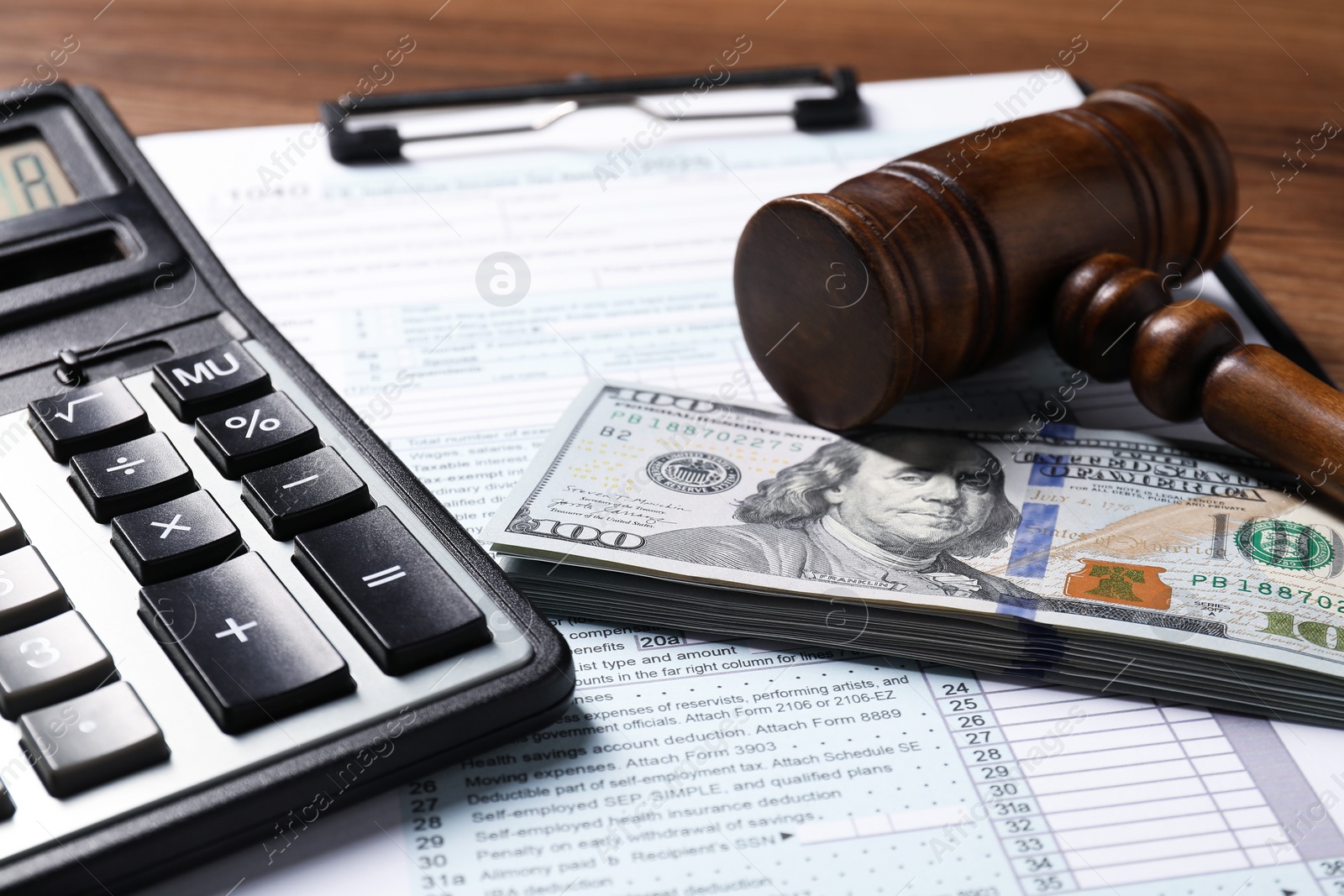 Photo of Tax return form, dollar banknotes, gavel and calculator on table, closeup