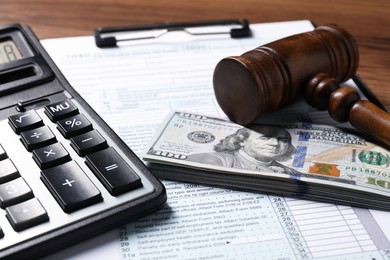 Photo of Tax return form, dollar banknotes, gavel and calculator on table, closeup