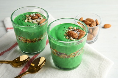 Glass cups of spirulina smoothie and spoons on table