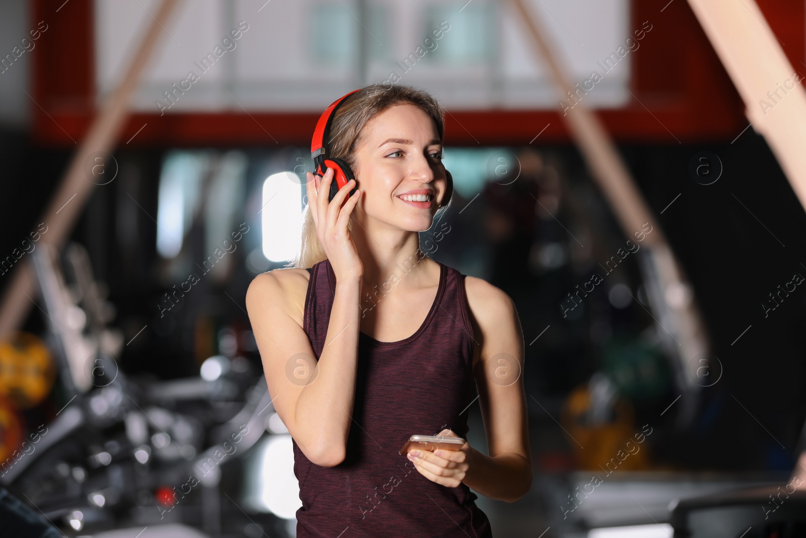 Photo of Young woman with headphones listening to music on mobile device at gym