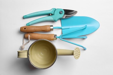 Watering can and gardening tools on white background, flat lay