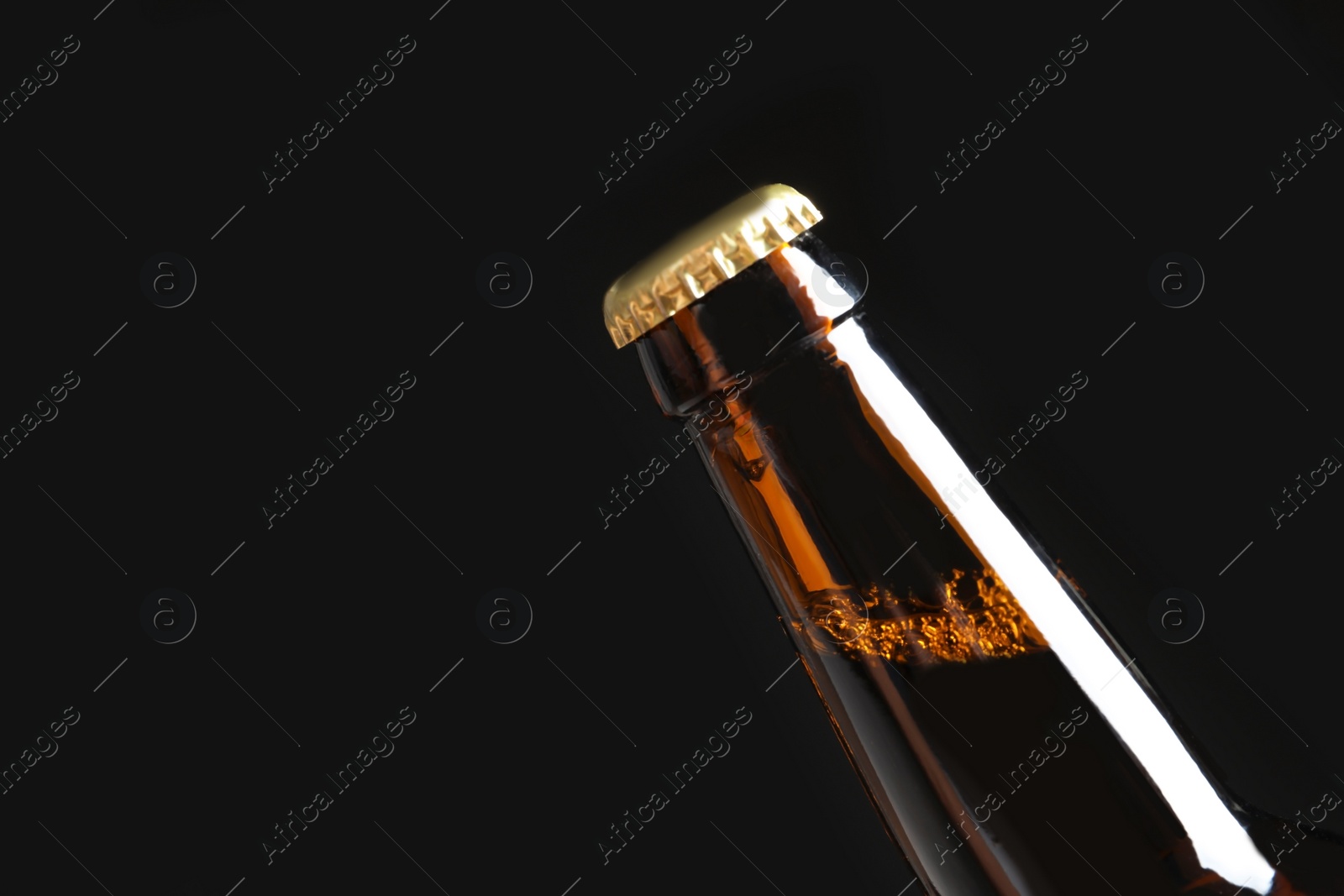 Photo of Bottle of tasty cold beer on black background, closeup