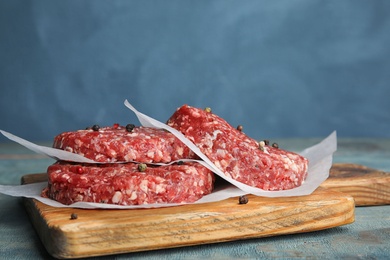 Photo of Raw meat cutlets for burger on blue wooden table. Space for text