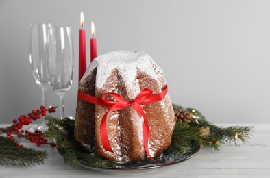 Delicious Pandoro cake with powdered sugar and Christmas festive decor on white wooden table. Traditional Italian pastry