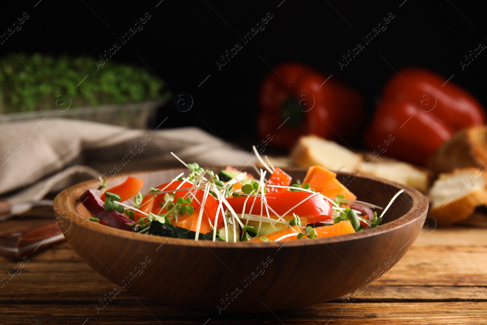 Photo of Salad with fresh organic microgreen in bowl on wooden table, closeup