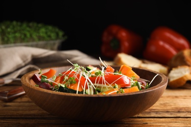 Salad with fresh organic microgreen in bowl on wooden table, closeup