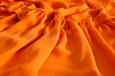 Texture of orange crumpled fabric as background, closeup view