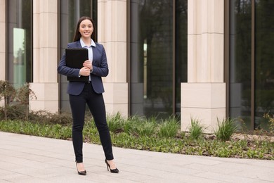 Photo of Female real estate agent with leather portfolio outdoors