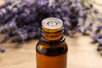 Photo of Bottle of essential oil and lavender flowers on table, closeup