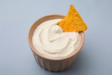 Photo of Delicious tofu sauce served with nachos chip in bowl on grey background, closeup
