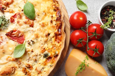 Photo of Tasty quiche with tomatoes, basil and cheese served on light table, flat lay