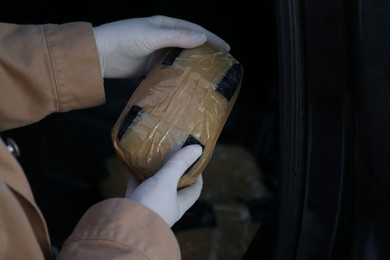 Man with package of narcotics on dark background, closeup. Space for text