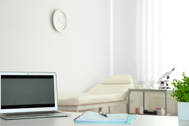 Modern laptop on desk in medical office, space for text. Doctor's workplace