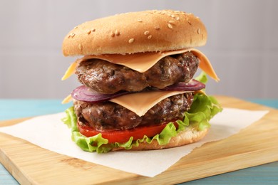 Photo of Tasty hamburger with patties, cheese and vegetables on table