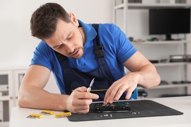 Photo of Male technician repairing hard drive at table indoors