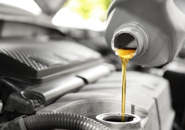 Photo of Pouring oil into car engine, closeup